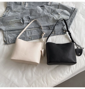 Detail view of cream and black pebbled leather bucket bags with adjustable straps