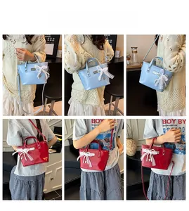Lace bow and pearl charm detail on a pastel blue leather bucket bag for women