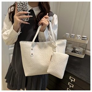 Detail of white woven tote bag with matching zippered pouch and gold rivet accents