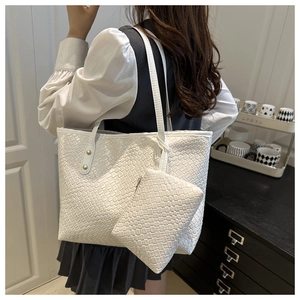Detailed view of a white woven tote bag set with a matching pouch shown on a model