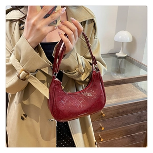 Détail du sac demi-lune rouge foncé avec texture vernie craquelée et logo blanc