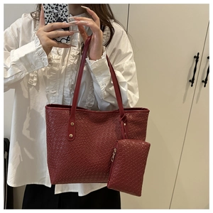 Detailed view of burgundy woven leather tote bag with gold rivets and matching pouch