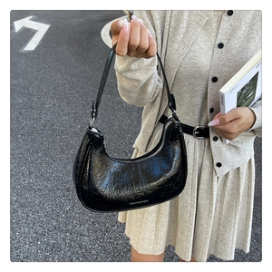 Détail du sac croissant en cuir verni noir avec texture plissée et fermeture éclair argent