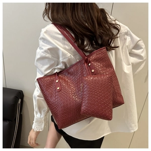 Detail of burgundy woven tote bag with matching zipper pouch on model's shoulder