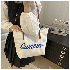 Détail du sac cabas en toile blanche avec broderie Summer bleue et des franges