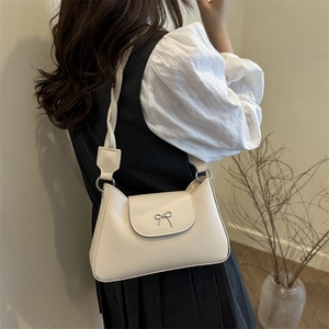 Chic cream white leather shoulder bag with a silver bow clasp for a minimalist aesthetic