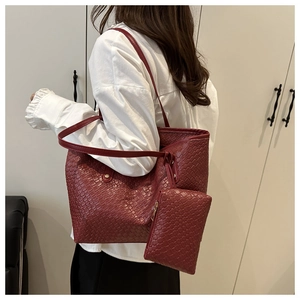 Detail view of woven leather tote bag and inner pouch on model in dark wine red