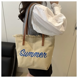 Détail du sac cabas en toile avec broderie Summer, bords frangés et bandoulière en cuir