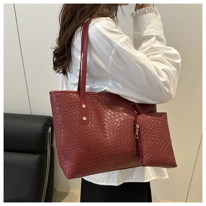 Detail of burgundy woven tote bag with a matching small zipper pouch on a side model view