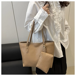 Detail of khaki woven tote bag showing reinforced golden metal studs and textured leather finish