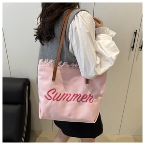 Dettaglio borsa tote in tela rosa con ricamo Summer, bordi a frange e manici in pelle marrone