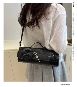 Macro shot of black crocodile texture baguette bag with golden hexagonal buckle detail