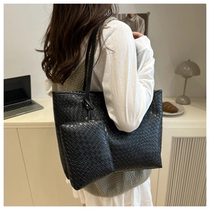 Detail of black woven large tote bag with matching coin purse in a cozy workspace setting