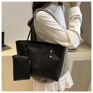Close-up of black woven tote bag and matching inner pouch with gold rivet details