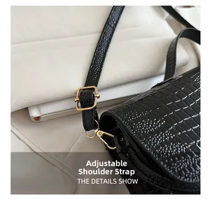 Close-up of black crocodile pattern bag featuring gold metal buckles and adjustable strap
