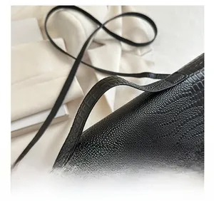 Detail of black crocodile pattern faux leather bag with gold geometric metal clasp