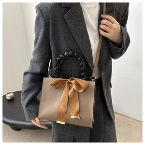Detail of khaki handbag with a large satin bow and chic black woven leather handle
