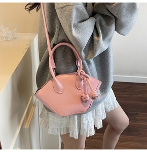 Détail du mini sac rose en forme de coquille avec breloques à nœud et bandoulière