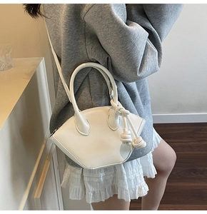 Gros plan d'un sac à main blanc en forme de coquillage avec un nœud en corde tressée