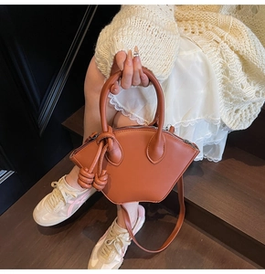 Détail du sac bandoulière marron en forme de coquille avec nœuds tressés et poignée