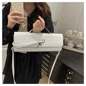 Detailed view of white crocodile pattern shoulder bag with golden geometric clasp