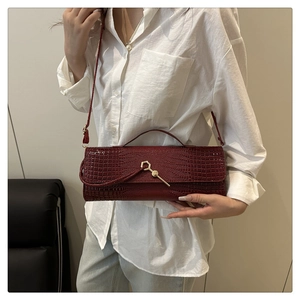 Close-up of burgundy crocodile pattern leather bag with unique gold metallic hardware
