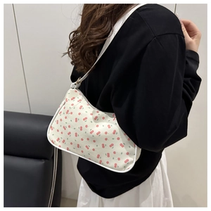 Side view of model wearing a small floral armpit bag with cherry prints and thin straps