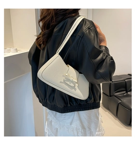 Detalle de bolso de cuero blanco crema con lazo en una modelo de estilo chic francés