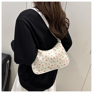 Détail du sac sous l'aisselle vintage avec motifs cerises rouges et bretelles blanches