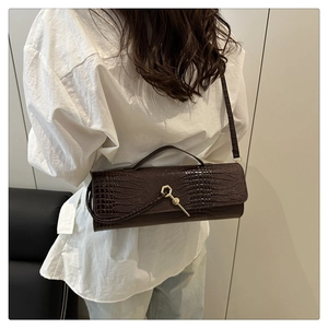 Detailed view of dark brown crocodile-embossed baguette bag with gold hexagonal lock