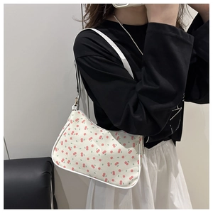 Detail of white underarm bag featuring red cherry prints worn by a model for size scale