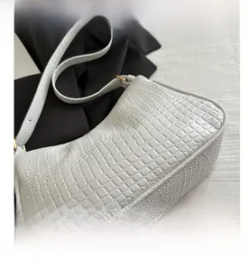 Detail of white crocodile pattern shoulder bag with glossy texture and gold buckle