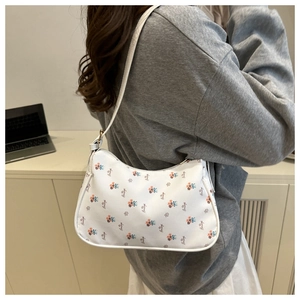 Détail d'un sac à bandoulière blanc avec imprimé fleuri et texture cuir sur un modèle