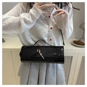 Detail of black crocodile texture baguette bag with unique golden hexagonal metal clasp