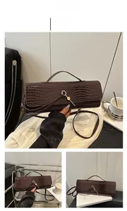 Detail of dark brown crocodile embossed baguette bag with golden hexagonal buckle