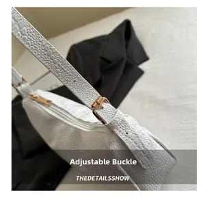 Detailed close-up of white crocodile texture leather with gold adjustable metal buckle