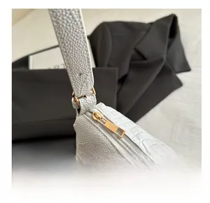 Detailed close-up of the smooth golden zipper and stitching on the white croc-pattern bag