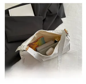 Internal storage view of white crocodile pattern bag showing wallet, lipstick, and earbuds