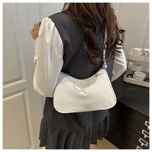 Model wearing a white crocodile pattern underarm bag with adjustable shoulder strap
