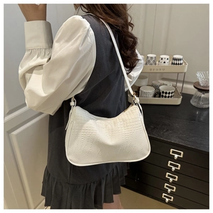 Detailed view of white crocodile pattern texture on a minimalist underarm shoulder bag