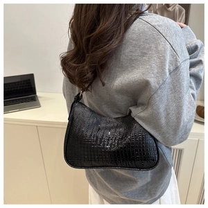 Detail of black crocodile pattern hobo bag worn by model for office commuter look
