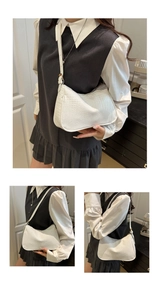 Detail view of white crocodile pattern shoulder bag with half-moon design and leather texture