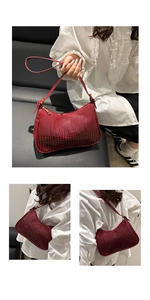 Detail of dark red croc-embossed underarm bag with glossy finish and gold zipper