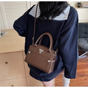Detail view of large dark brown leather handbag with metal buckle and shoulder strap