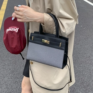 Fashionable bicolor leather handbag with gold twist lock and adjustable shoulder strap
