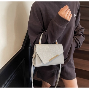 Detail of grey crossbody bag featuring sparkling silver glitter flap and gold metal trim