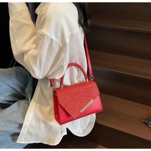 Detail of red sequin handbag with luxury golden metal bar and glossy finish textures