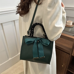 Sac à main élégant en cuir vert foncé avec nœud en satin bleu et détail de poignée tissée