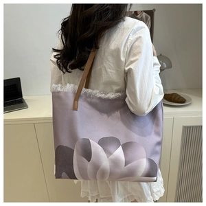 Detalle del bolso tote de lona morada con estampado floral y bordes deshilachados