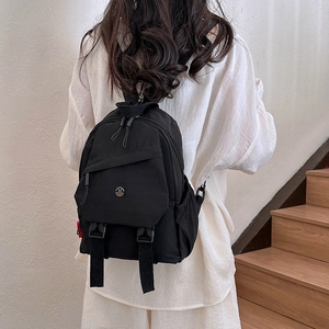 Minimalistische zwarte nylon mini-rugzak voor dames met gespen en metalen embleem